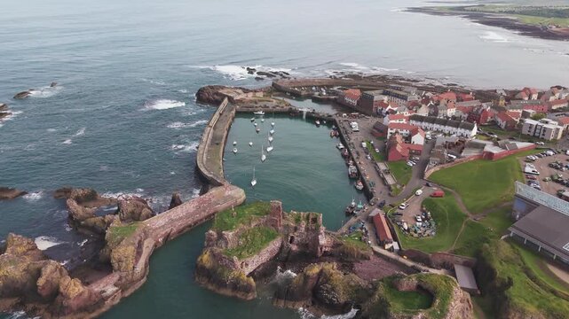 Dramatic aerial view of Dunbar Castle ruins on rocky cliffs above the North Sea, Scotland.