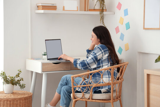 Young woman working with blank laptop at table in office