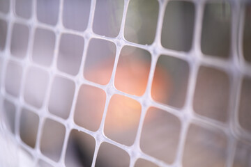 Abstract white plastic grid with warm bokeh background © 可意 张
