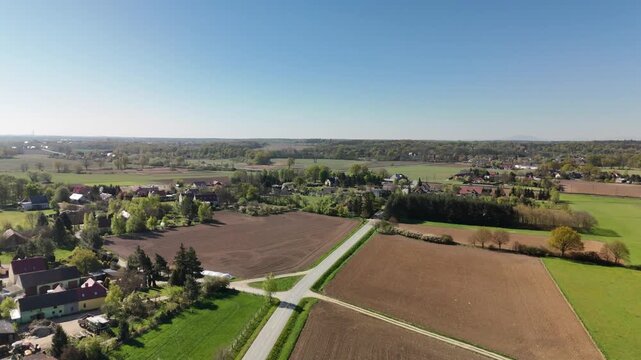 Aerial view of a rural village with houses fields and a road on a flat plain in Poland in spring