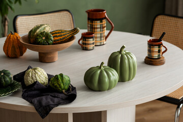 Naklejka premium Autumn harvest decoration with pumpkins and gourds on a stylish table, perfect for seasonal inspiration and comfortable home aesthetics