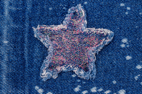 Star patch sewn onto blue denim fabric showing texture and design details during daylight hours