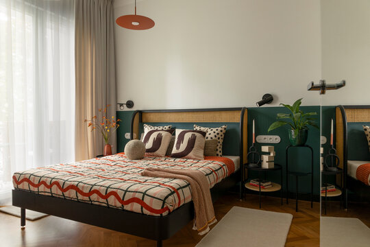 Inviting bedroom with modern decor, patterned bedding, natural light, and green accents for a comfortable home interior