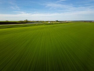 Fototapeta premium Dynamic motion blur aerial of green field and road with car