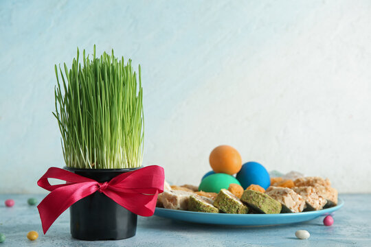 Green wheat grass, traditional sweets and eggs on blue table. Nowruz Bayram celebration
