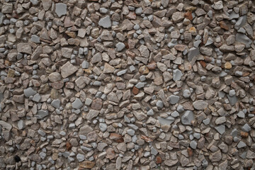 Close-up texture of a pebble dash wall. Detailed background of small beige and grey stones embedded in concrete, creating a rough architectural surface for design. © Tetiana