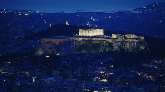 Aerial panoramic blue hour shot of illuminated Acropolis in Athens, Greece with Parthenon temple landmark, panoramic view ov Athens cityscape with Piraeus port at background
