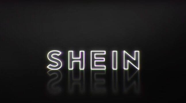 Illuminated shein displaying a popular online clothing retailer, reflecting on a dark, glossy surface, representing e-commerce and fast fashion