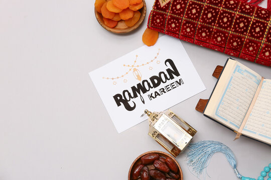 Greeting card, prayer beads, Koran and dried apricots on grey background. Ramadan celebration