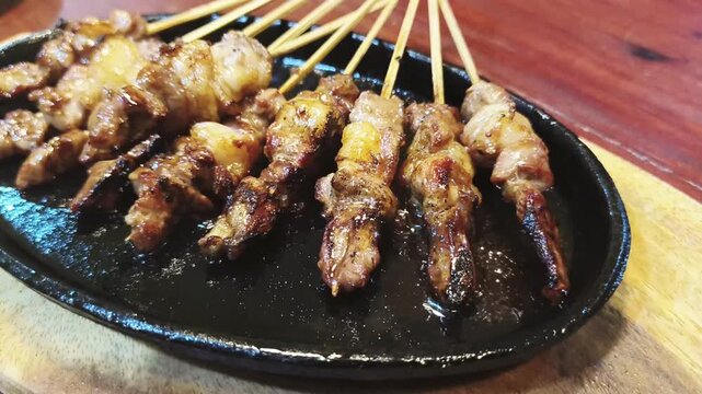 Goat grilled satay skewers on hot plate, Indonesian street food close up