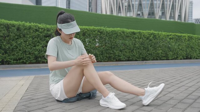 Sporty athletic woman runner with sportswear holding sore knee on park running path, sprained knee, sports pain concept for healthcare physiotherapy, outdoor fitness setback during marathon training