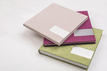 Fototapeta premium The colorful fabric wedding photo albums with mockup for engraving on the cover on a wooden table. Soft focus. Memory books. Family photos archive saved in brightly designed photo book.