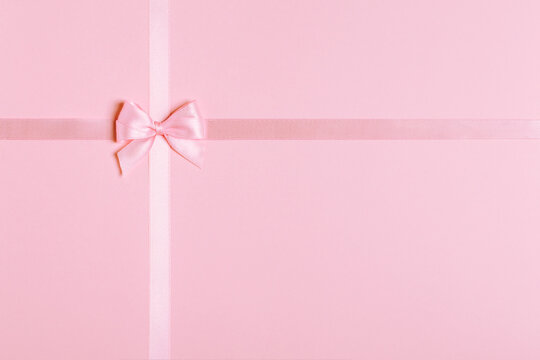 Pink satin ribbon and bow on pink background with copy space