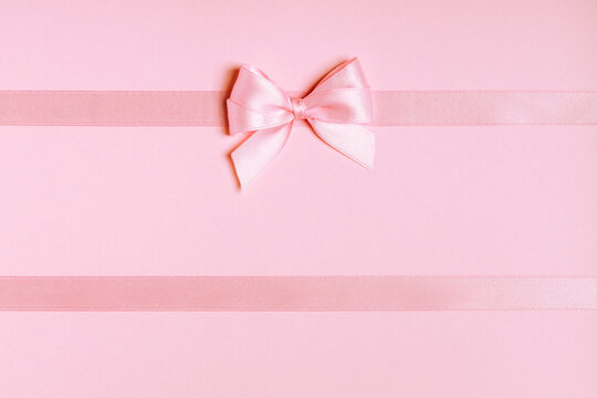 Pink satin ribbon bow on horizontal ribbons with copy space