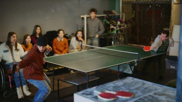 A diverse group of students plays ping pong together in a casual setting. Friends enjoy an inclusive table tennis match and cheer.