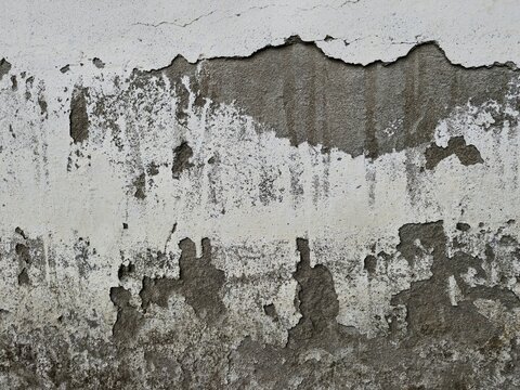 White concrete wall damaged by spalling of plaster