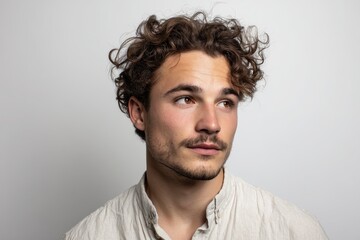 Obraz premium Head-and-shoulders portrait of a stylish young man with a thoughtful, unsure look in neutral light