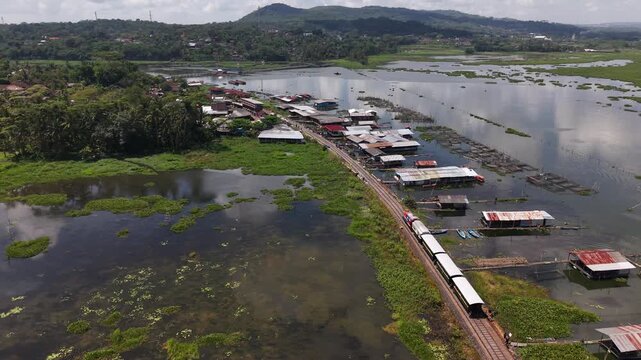 An aerial view of the Ambarawa Museum's vintage train journey across Lake Rawa Pening. A nostalgic journey using a diesel locomotive and classic wooden carriages.