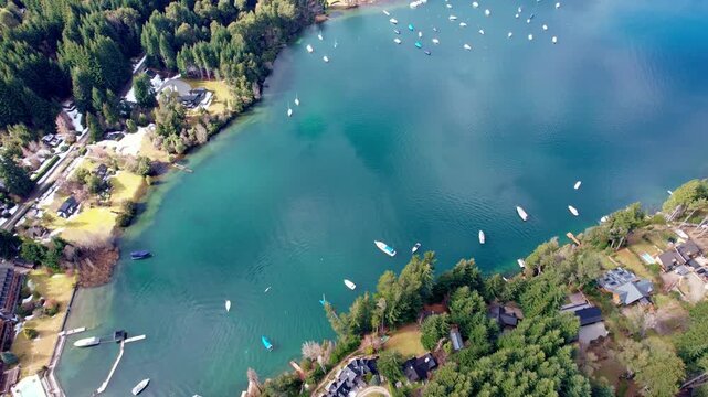 Slow forward drone movement with a steep downward camera angle over a calm bay. The crystal clear turquoise water reveals boats and shoreline details in Patagonia.