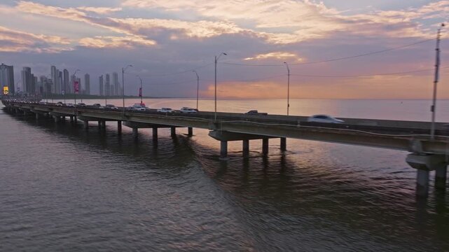 Aerial drone shot during sunrise in Panama City following the route of the Corredor Sur and revealing Costa del Este in the background