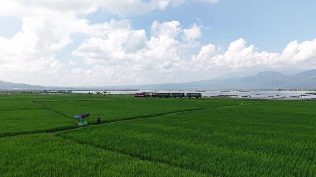An aerial view of the Ambarawa Museum's vintage train journey across Lake Rawa Pening. A nostalgic journey using a diesel locomotive and classic wooden carriages.