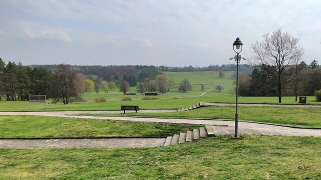 Peaceful landscape in Lidice with green fields, walking paths and benches under a soft cloudy sky. This place in the Czech Republic carries quiet atmosphere of memory, history and reflection.