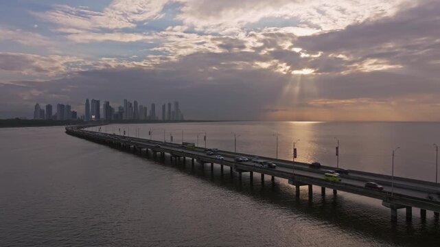 Aerial drone shot of the morning sun rays and the Corredor Sur of Panama with the city of Costa del Este in the background