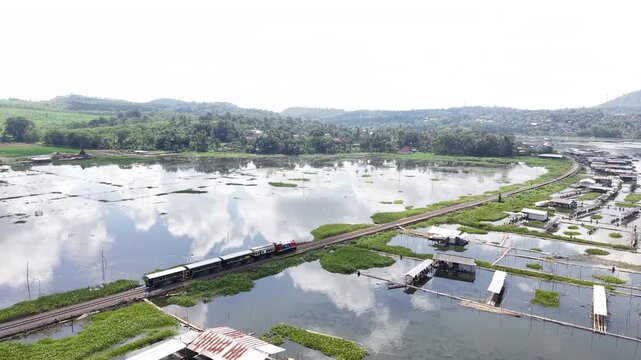 An aerial view of the Ambarawa Museum's vintage train journey across Lake Rawa Pening. A nostalgic journey using a diesel locomotive and classic wooden carriages.