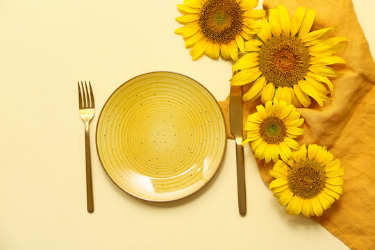 Beautiful table setting with sunflowers on yellow background