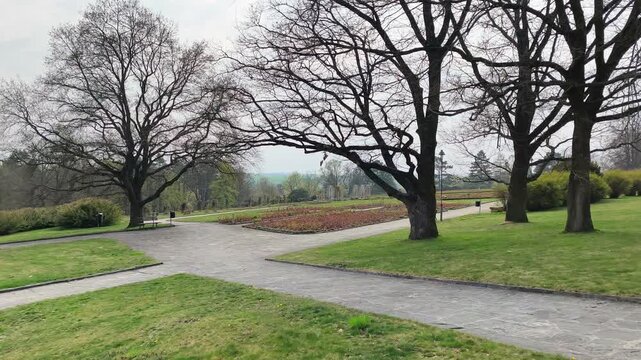 Quiet park landscape in Lidice with large trees, pathways and open green space under overcast sky. Historic location in the Czech Republic offering calm atmosphere and sense of remembrance.