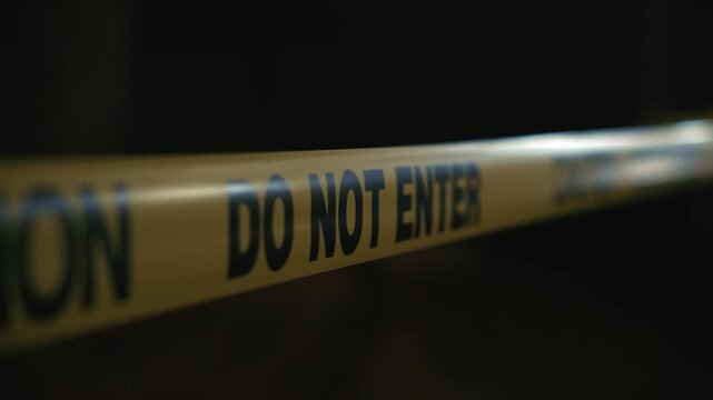 Yellow caution tape do not enter restricting access to dangerous zone at night indicating increased risk and perimeter control in dark outdoor environment