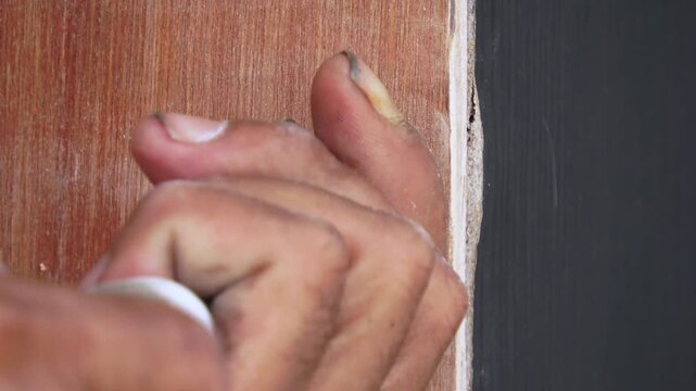 A high-angle, close-up shot of a man's hands working on a DIY project. The handheld footage captures the authentic movement as his right hand uses a manual screwdriver to secure a metal bolt into a pi