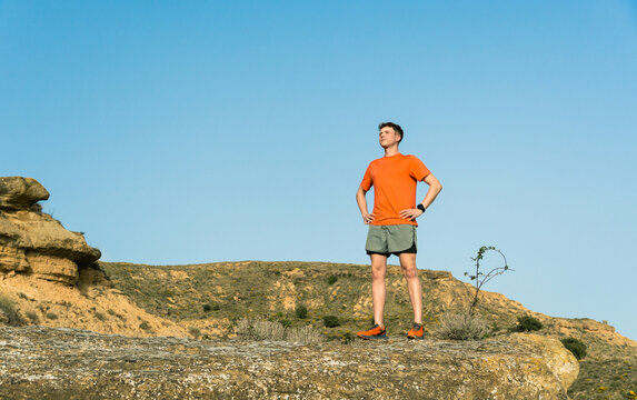 Runner standing on a desert hill looking forward