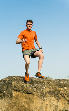 Young man trail running jumping over rock outdoors