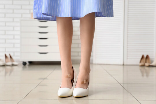 Legs of young woman in high heel shoes with callus patches at home