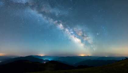 Fototapeta premium Milky Way arcing over tranquil mountain ridge at night.