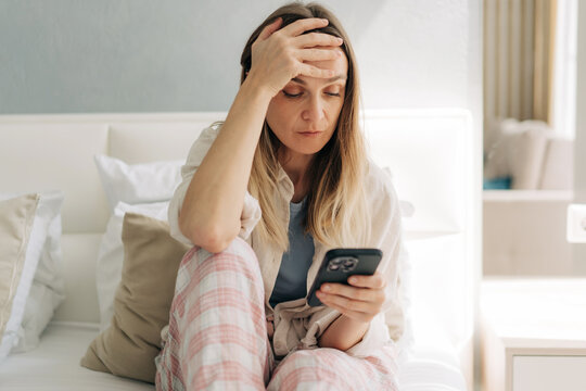 Upset mature woman looking at her mobile phone at a health monitoring application.