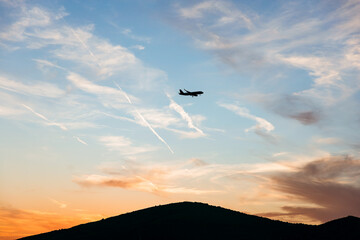 Fototapeta premium Airplane Silhouette at Sunset Over Mountain Bay