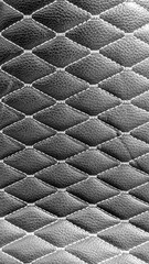 Fototapeta premium Black leather quilted upholstery with white stitching creating a diamond pattern, representing luxury, elegance, comfort, and high quality craftsmanship in design and fashion texture