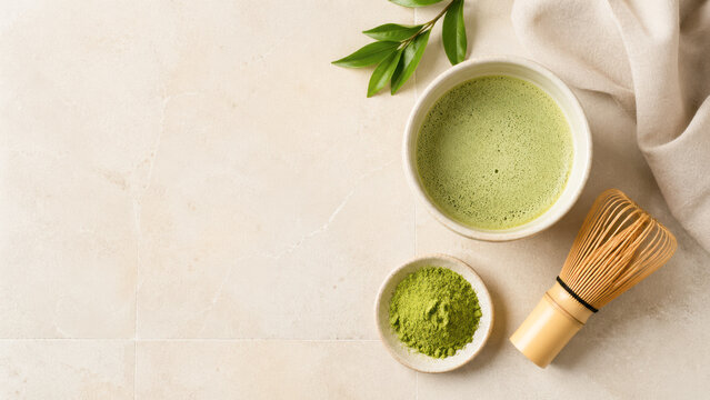 Ceremonial matcha tea with bamboo whisk, matcha powder, and green leaves on a light surface, styled for a calming tea preparation scene.