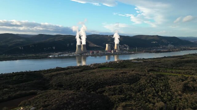 Cruas, France - 20 February 2026: Cinematic drone flyover above the Cruas nuclear power station in France, showing massive cooling towers with steam rising near the Rhone River and surrounding country