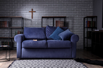 Interior of living room with Holy Bible on sofa and bookshelves © Pixel-Shot