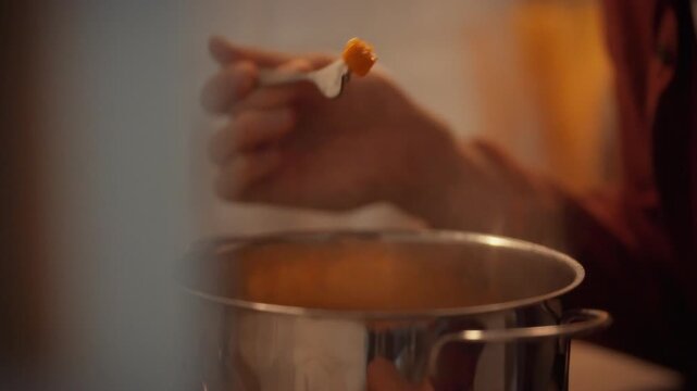 In home kitchen, a man tastes a forkful of pumpkin to check if the vegetables are cooked, a crucial step in preparing a delicious vegetable stew as part of a traditional recipe for a nutritious dinner