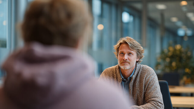 a male social worker is talking to a young person at a table