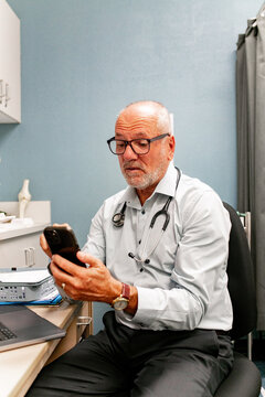 Doctor attentively using smartphone in medical office