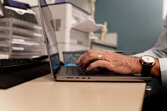 Close‑up of hands typing on laptop in office workspace