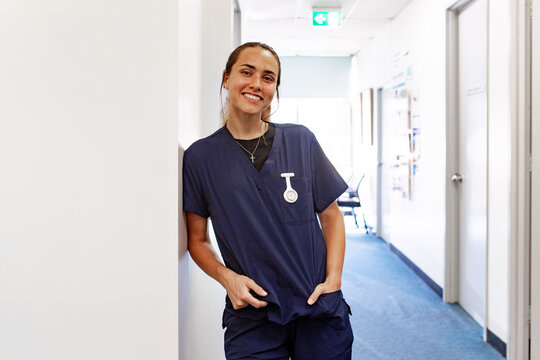 Female nurse in scrubs standing in clinic hallway