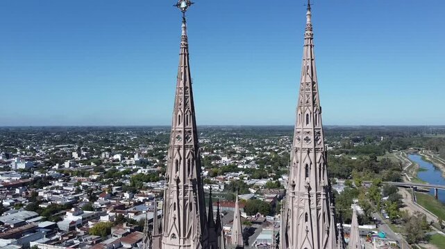 Aerial drone shot rising above the Basilica de Lujan towers up to the crosses with a view of the city in Lujan, Buenos Aires, Argentina.