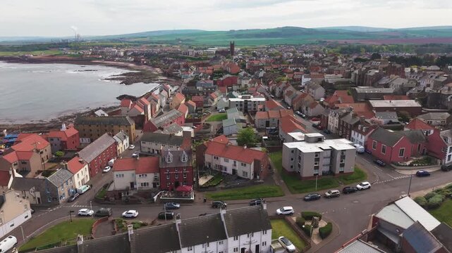 Cinematic aerial flyover above a coastal Scottish town with traditional architecture and sea view