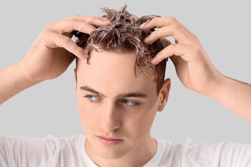 Fototapeta premium Young man washing hair against light background